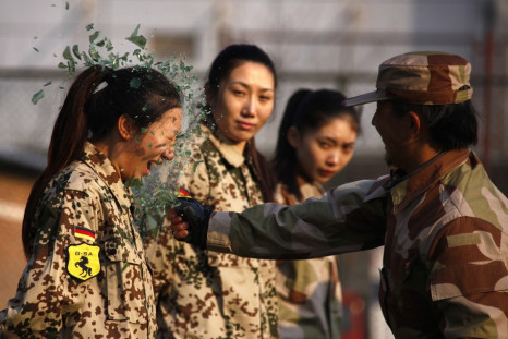 An instructor from Tianjiao Special Guard Consultant Ltd smashes a bottle over a female recruit's head during a training session