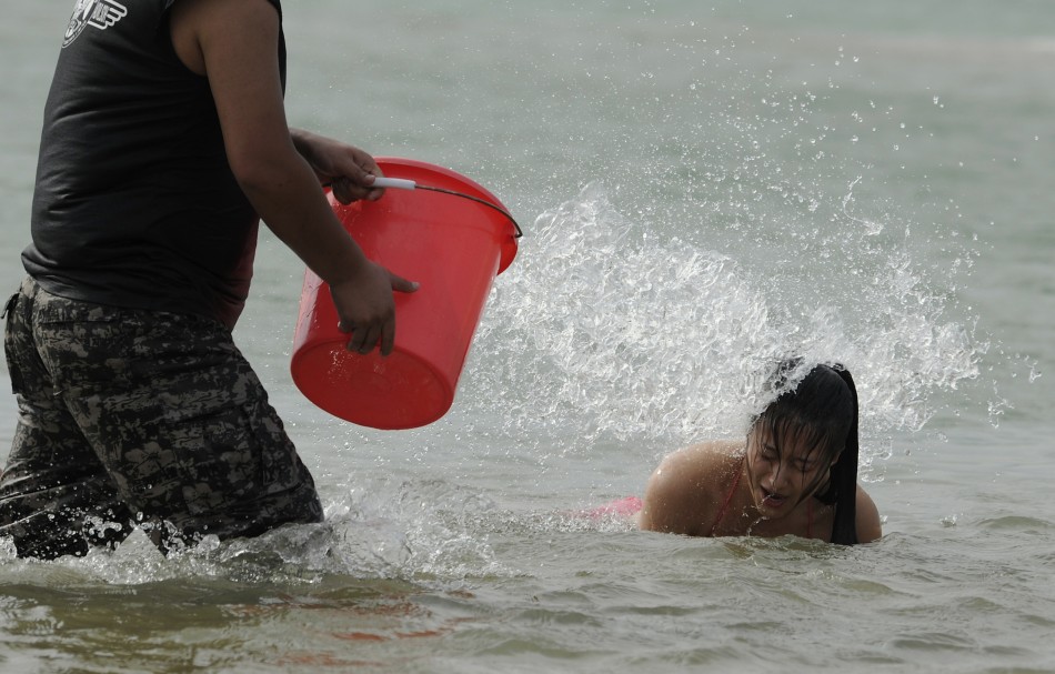 A recruit is surprised to be drenched with a bucket of water as she emerges from the sea in Sanya, Hainan province, China A recruit is surprised to be drenched with a bucket of water as she emerges from the sea in Sanya, Hainan province, China