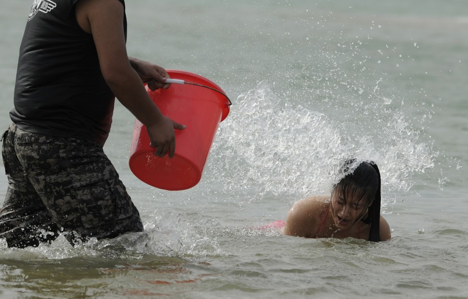 A recruit is surprised to be drenched with a bucket of water as she emerges from the sea in Sanya, Hainan province, China