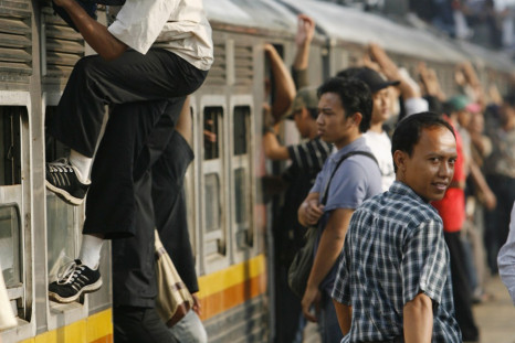 Indonesians climb on to the top of a train, a practice known as roof riding or train surfing