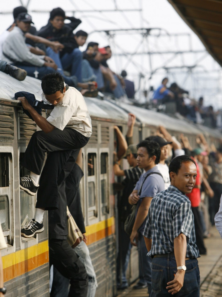 Indonesians climb on to the top of a train, a practice known as roof riding or train surfing