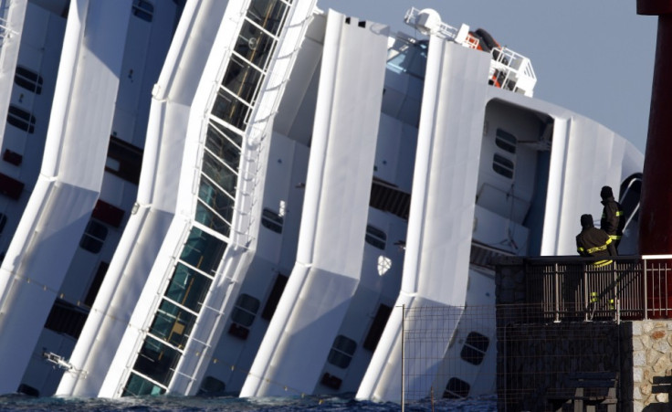 Two firefighters watch the Costa Concordia cruise ship that ran aground off the west coast of Italy, at Giglio island