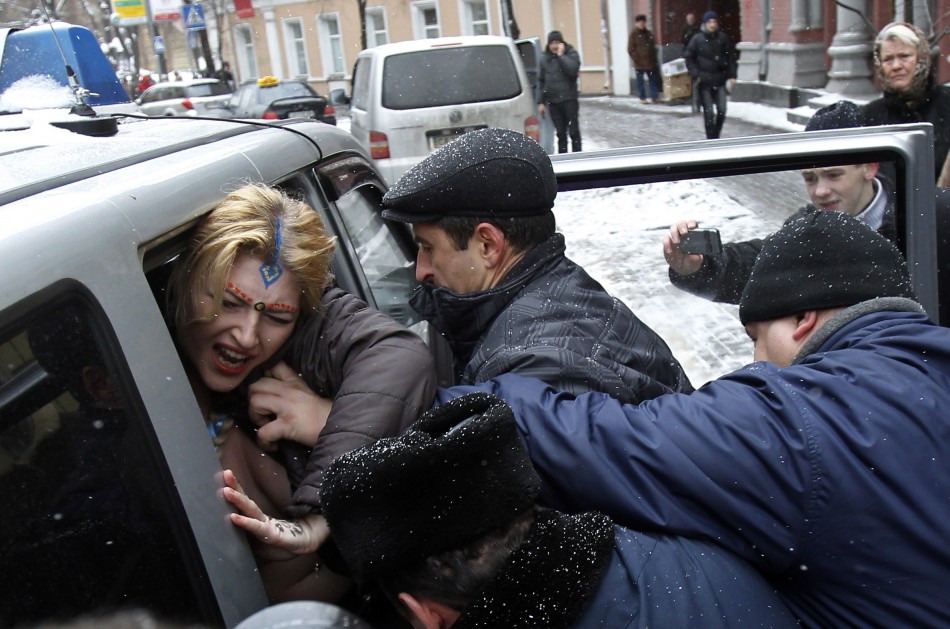 An activist from womens rights group Femen is detained during a protest outside the residence of the Indian ambassador in Kiev