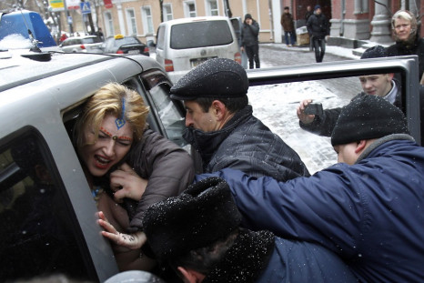 An activist from women's rights group Femen is detained during a protest outside the residence of the Indian ambassador in Kiev