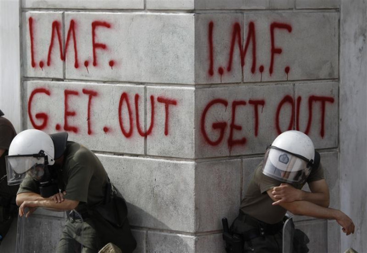 Greek riot policemen rest in front of graffiti during violent demonstrations over austerity measures in Athens