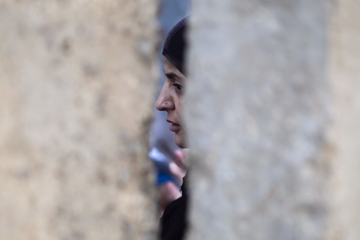 A Palestinian woman waits behind a wall