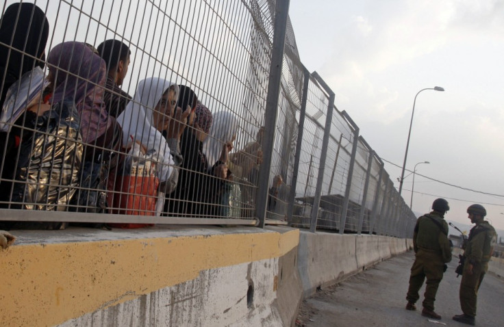 Israeli soldiers stand guard as Palestinians wait to cross the Hawara checkpoint near the West Bank city of Nablus