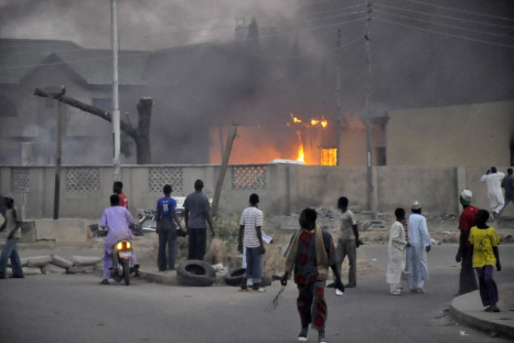 People surround a burning car after Boko Haram attacked a police station in Kano