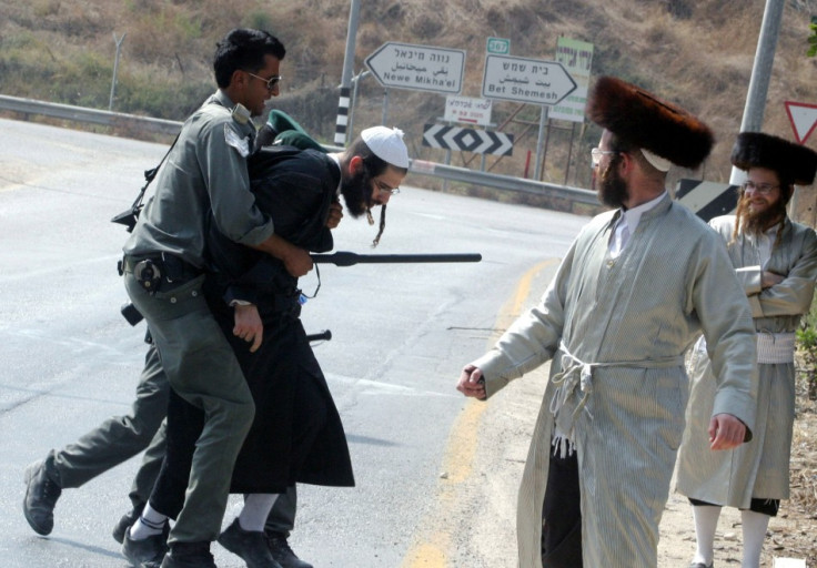 An Israeli border police officers detains an Ultra-Orthodox Jewish man