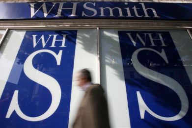 Pedestrians walk past a WH Smith shop in London