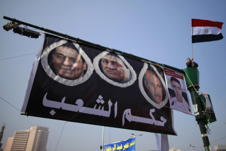 A demonstrator waves an Egyptian flag next a poster of former President Hosni Mubarak and Field Marshal Mohamed Hussein Tantawi during a protest marking the first anniversary of Egypt's uprising at Tahrir square, in Cairo