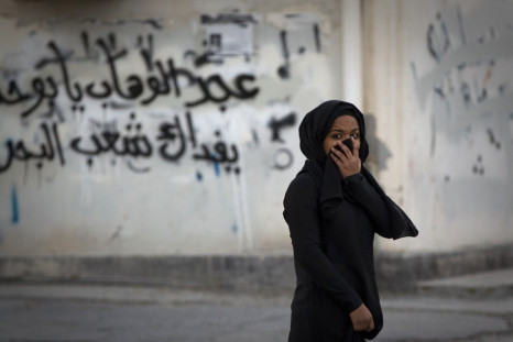 A woman covers her face during a standoff with police after a mourning procession on the third day after the death of Yassin Al-Afsoor in the village of Mameer