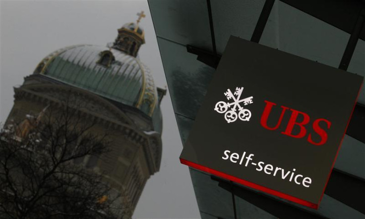 A UBS logo is pictured on a UBS bank building in front of the Swiss federal parliament building in Bern