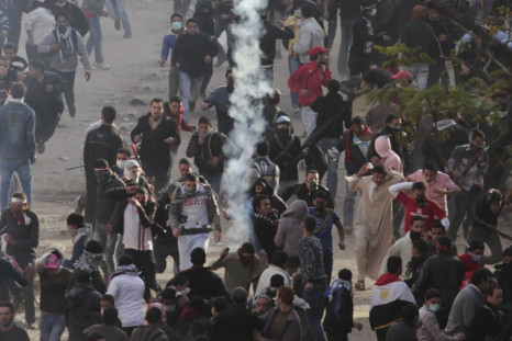 Protesters run from tear gas thrown by police forces during clashes near the Interior Ministry in Cairo