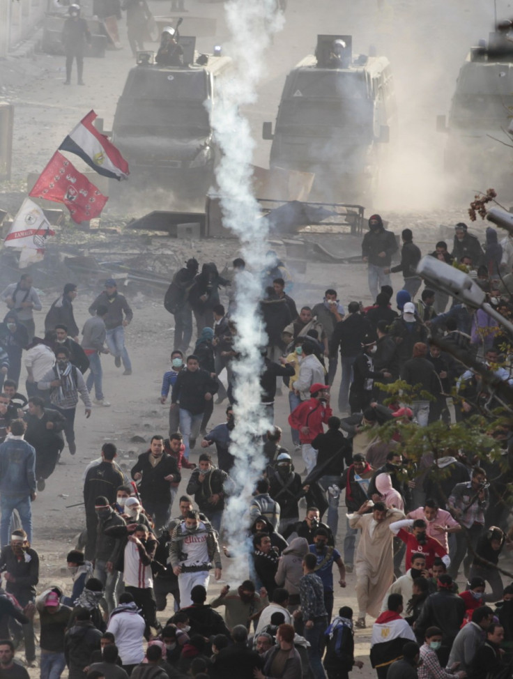 Protesters run from tear gas thrown by police forces during clashes near the Interior Ministry in Cairo