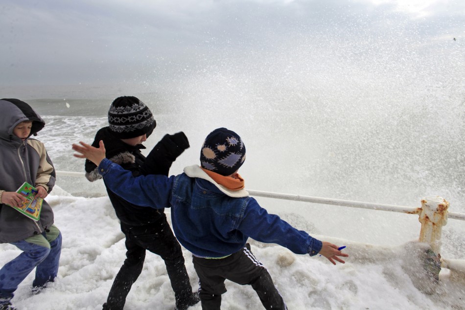 Children play as waves hit the frozen shore in the Black Sea harbour of Constanta