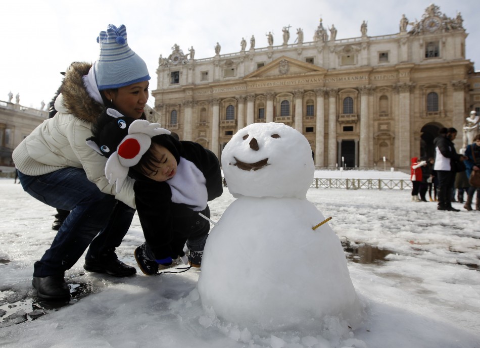 A mother with her son look at a snowman at San Peter square in Vatican