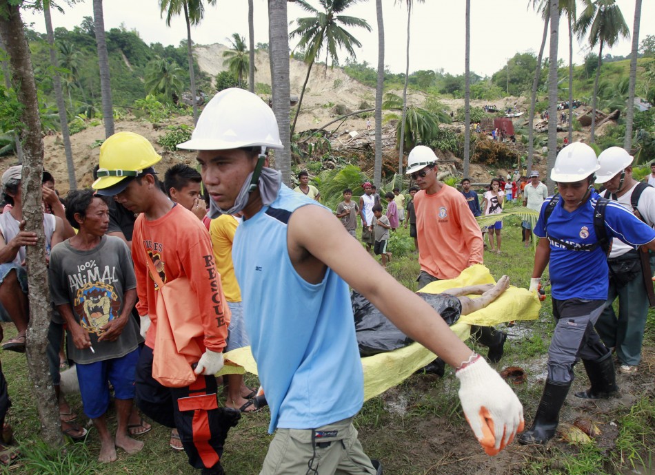 Rescuers carry a body retrieved from a landslide