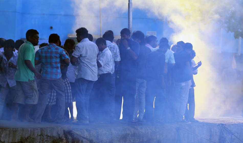 Supporters of ousted Maldivian President Nasheed take cover from tear gas and smoke during a clash in Male