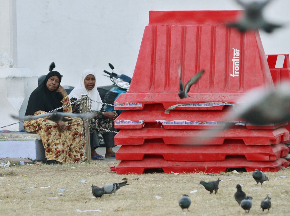 Women sit next to plastic barriers used during Tuesdays protests in Male