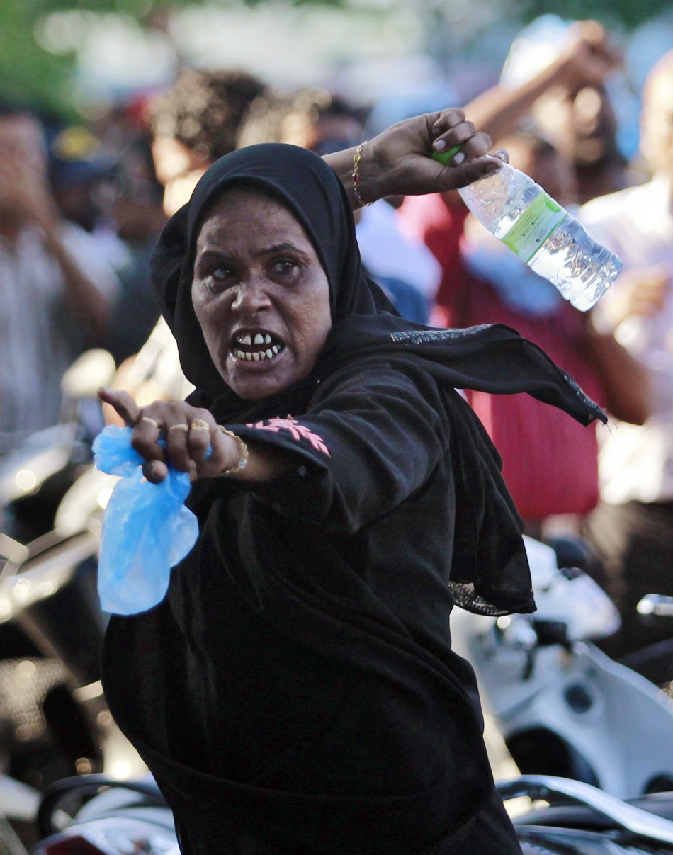 A supporter of ousted Maldivian president Nasheed throws a bottle at riot police officers during a clash in Male