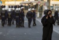 A protester gestures at the camera after passing a police patrol in Manama