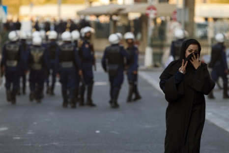 A protester gestures at the camera after passing a police patrol in Manama