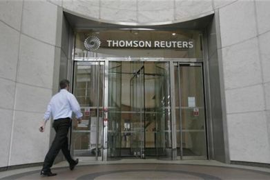 A worker enters the Thomson Reuters building in the Canary Wharf financial district of London