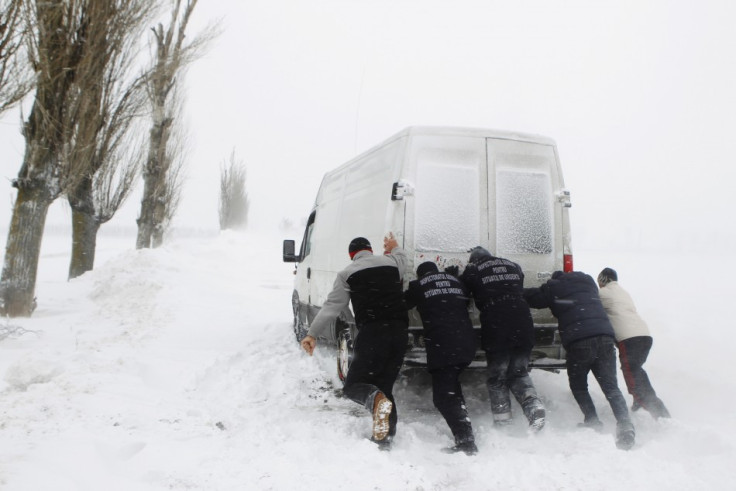 Men push van stalled on road during heavy snowfall near Glodeanu Silistea village in Romania