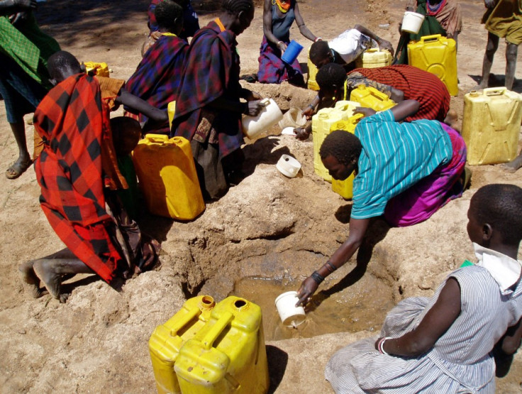 gandan women and children collect water from a hole dug in a dry riverbed at Kaabong village, Karamoja region
