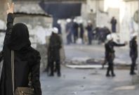 A protester shows a victory sign to riot police during clashes in Bahrain