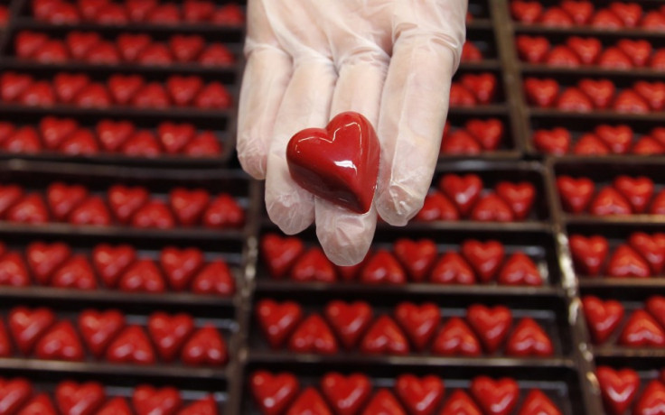 A worker displays a heart-shaped praline