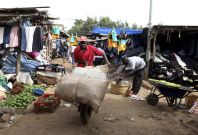 Man pushes handcart through market in Kibera, Nairobi