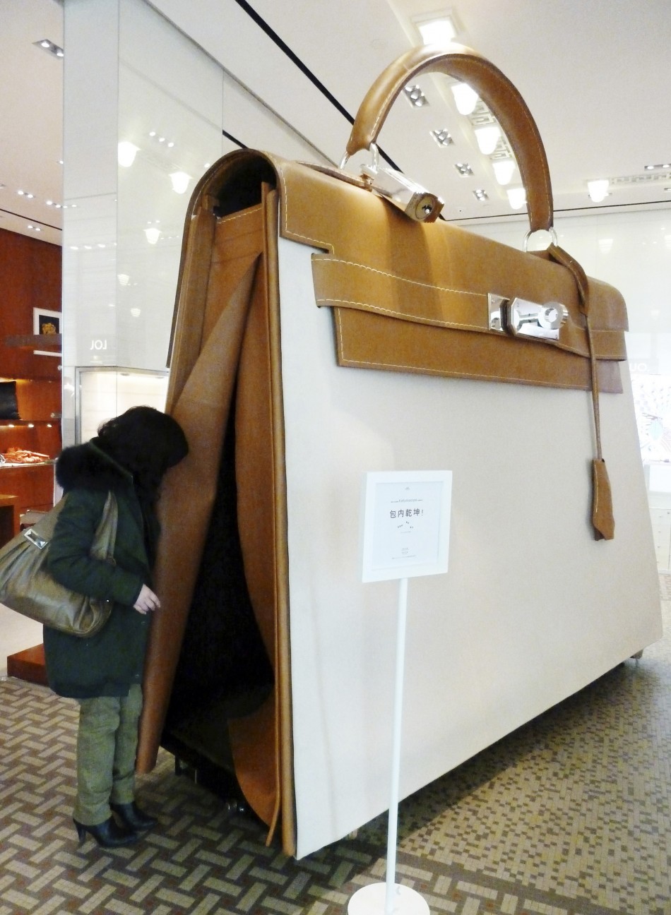 A customer looks into a giant Hermes Kelly handbag at a Hermes boutique in Nanjing