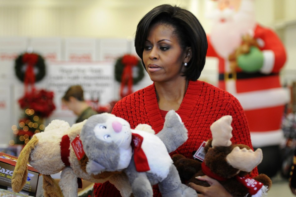 Obama carries stuffed toy animals as she helps sort toys for boys and girls as she visits the Toys for Tots distribution center at Joint Base Anacostia-Bolling in Washington