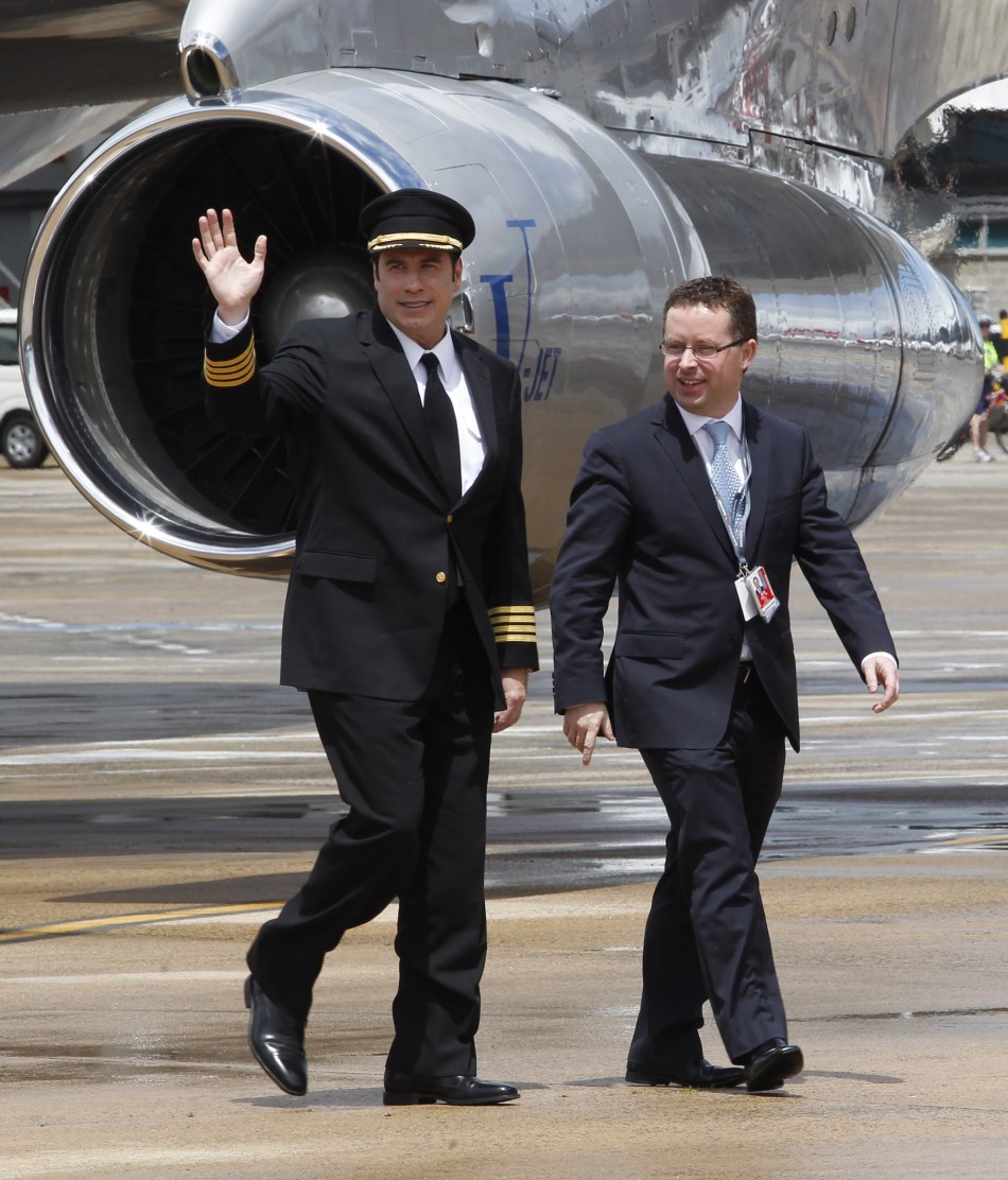 U.S. actor John Travolta waves as he walks with Qantas Chief Executive Officer