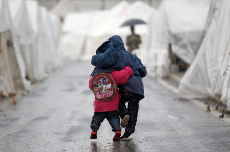 Syrian boys walk shoulder to shoulder in the rain at the Boynuyogun refugee camp on the Turkish-Syrian border in Hatay