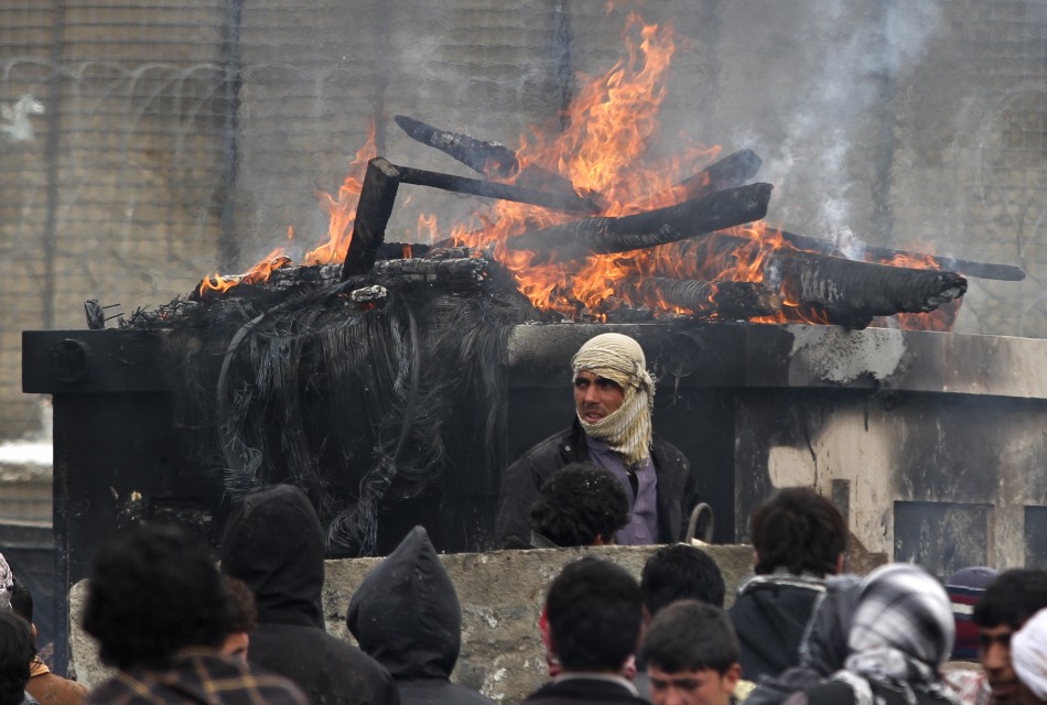 Afghan men stand near a pile of wood and tyres, set on fire by the protesters, during a protest outside the U.S. military base in Bagram Afghan men stand near a pile of wood and tyres, set on fire by the protesters, during a protest outside the U.S. military base in Bagram