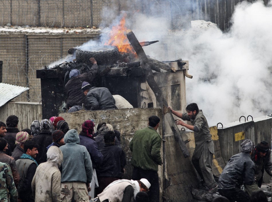 Afghan men stand near pieces of wood and tyres which they set on fire during a protest outside the U.S. military base in Bagram, north of Kabul Afghan men stand near pieces of wood and tyres which they set on fire during a protest outside the U.S. military base in Bagram, north of Kabul