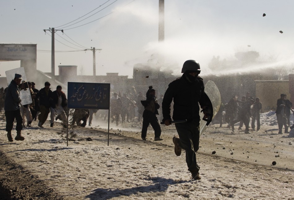 An Afghan policeman runs away as protesters throw rocks near a U.S. military base in Kabul