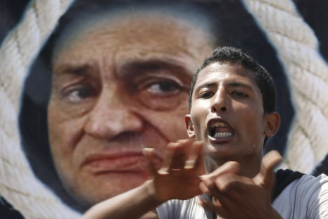 An anti-Mubarak protester shouts slogans in front of a poster depicting Mubarak with a noose in Cairo