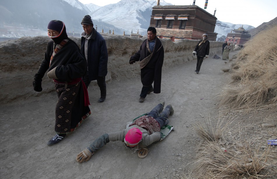 An ethnic Tibetan woman prostrates as she prays near the Labrang Monastery in Xiahe county, Gansu Province