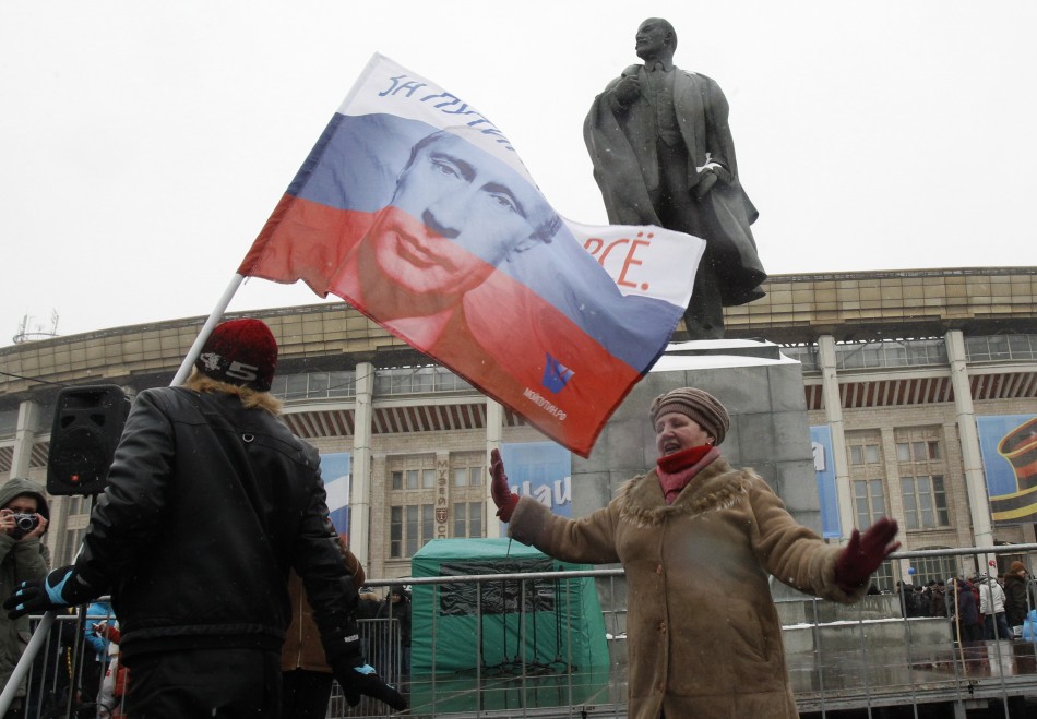 Woman dances outside stadium in front of statue of Vladimir Lenin, founder of Soviet state