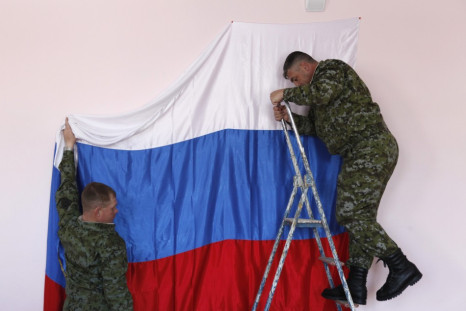 Russian soldiers hang their national flag at a polling station