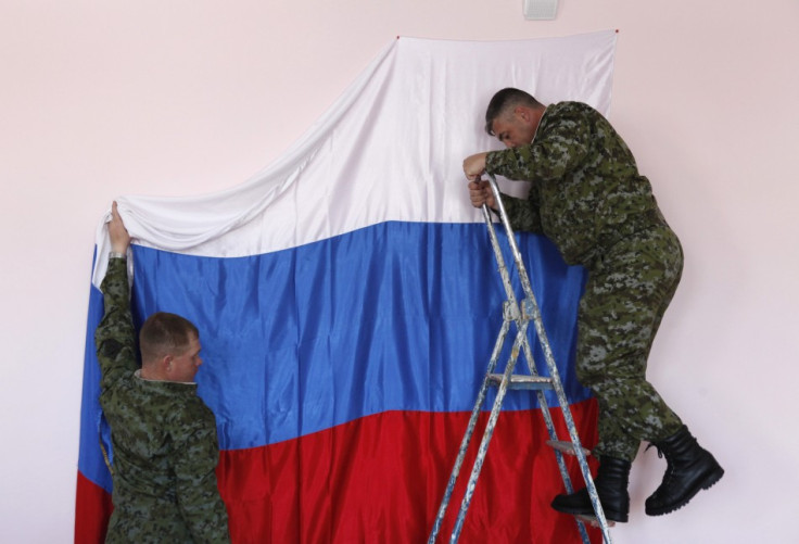 Russian soldiers hang their national flag at a polling station