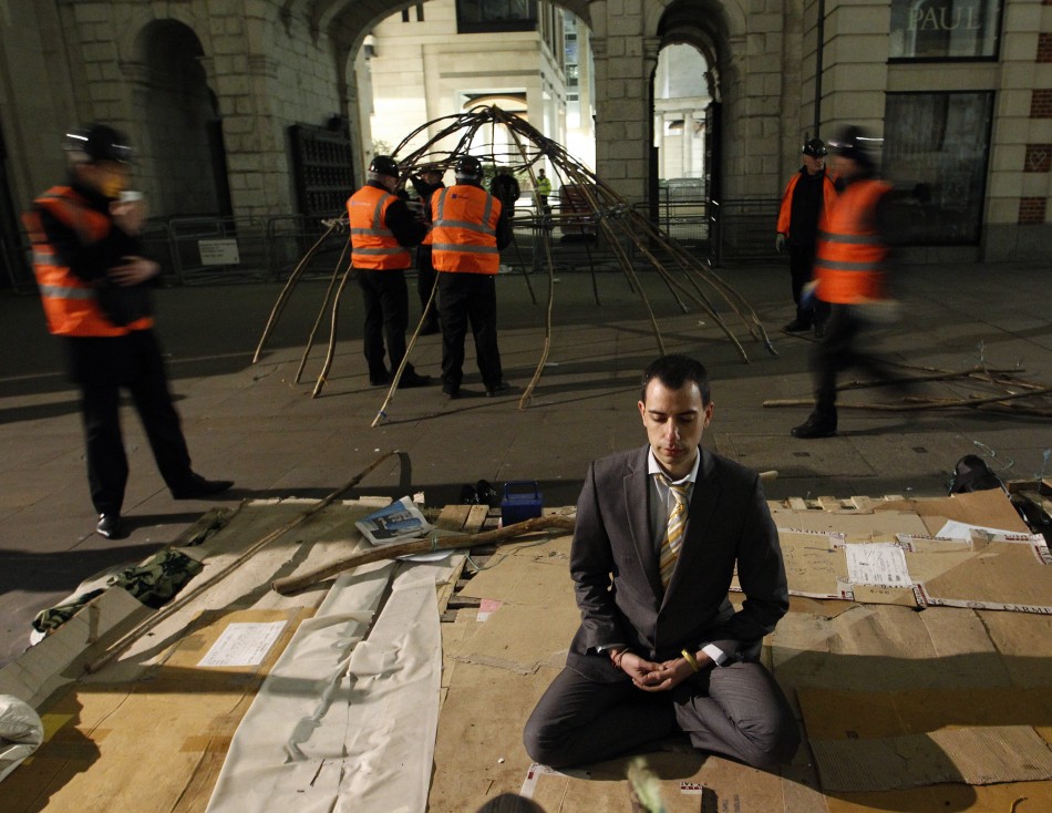 A protester meditates in front of a statue of Buddha as bailiffs dismantle the frame of his tent behind him during the eviction of the Occupy encampment outside St Paul039s Cathedral in London