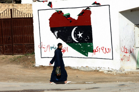 A man walks past a wall painted with a graffiti with colours of the ruling National Transitional Council in Zintan