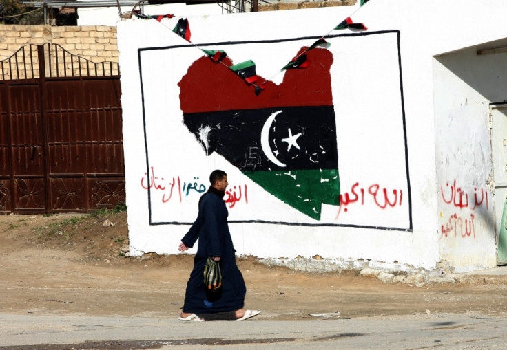 A man walks past a wall painted with a graffiti with colours of the ruling National Transitional Council in Zintan