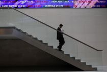 A man walks down steps under a share price ticker at the London Stock Exchange in the City of London