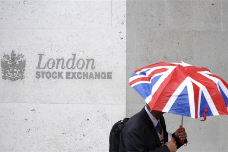 A worker shelters from the rain as he passes the London Stock Exchange in the City of London